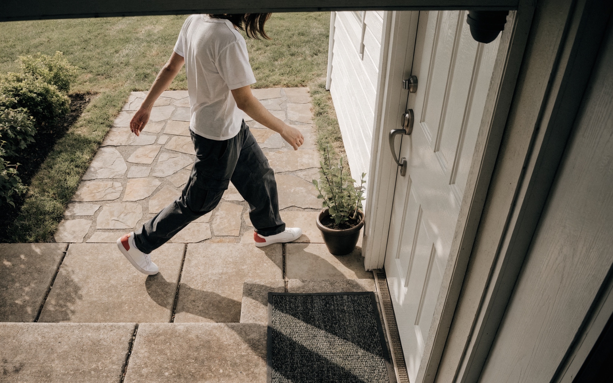 Doorbell-camera view looking down at a front porch: a person walking up the walkway toward the door