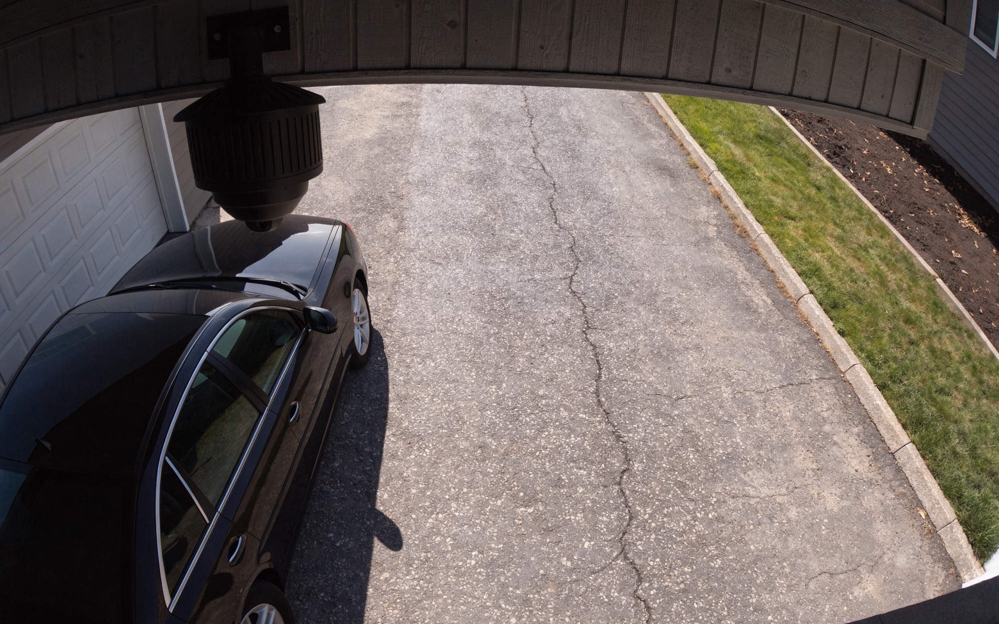 Driveway security-camera view looking down: a car parked in the driveway